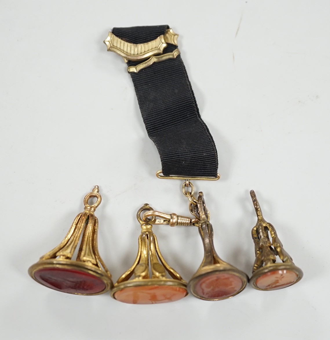 Four assorted 19th century gold plated and agate or hardstone set oval fob seals, largest 37mm, two matrices carved with busts and two with animals.